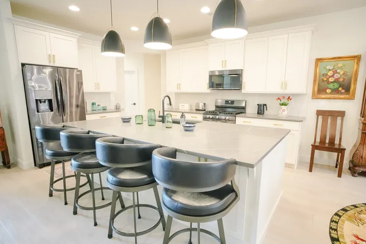 Kitchen featuring a large central island with seating, white cabinetry, light countertops, stainless steel appliances, and wood-finish flooring