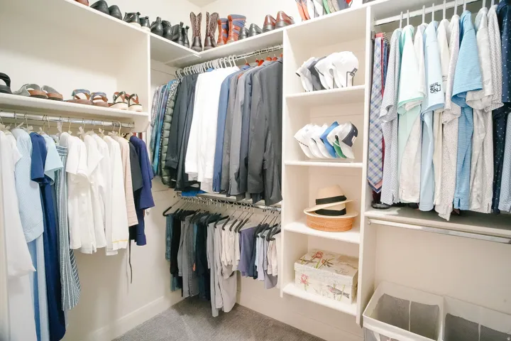 Walk-in closet featuring white built-in shelving, multiple hanging rods, and plush gray carpeting