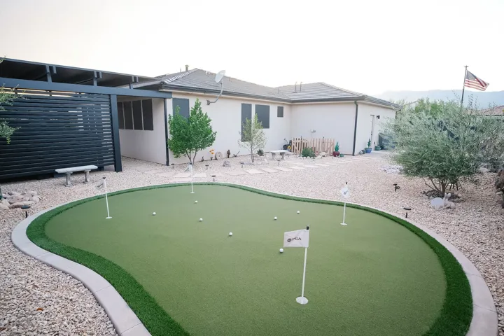 Backyard featuring a multi-hole putting green, gravel landscaping, and a covered patio structure