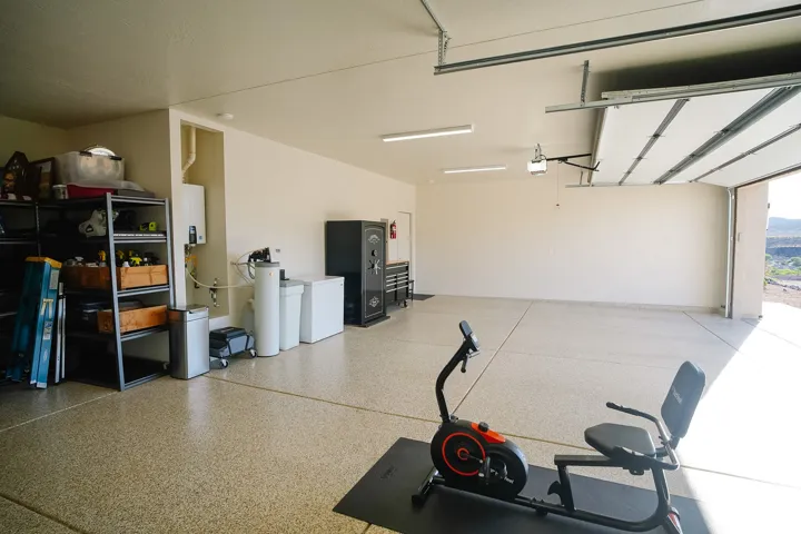 Spacious garage featuring a durable epoxy floor, bright overhead lighting, and an overhead garage door