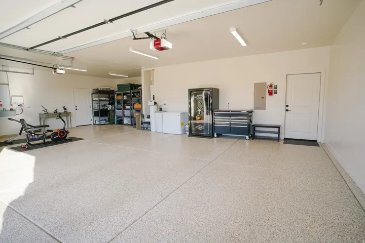 Spacious garage featuring a finished epoxy floor, multiple overhead garage door openers, and recessed lighting