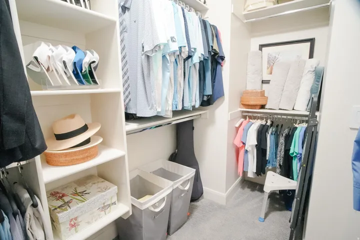 Custom closet system featuring built-in shelving, multiple hanging rods, and light gray carpeting