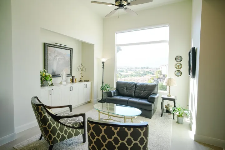 Living area featuring high ceilings, a built-in storage cabinet with white shaker-style doors, and expansive windows