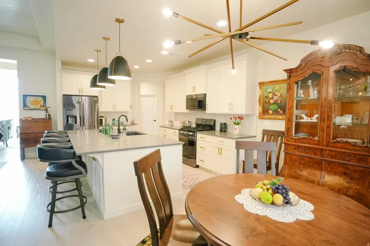 Spacious kitchen featuring an expansive island with undermount sink, white cabinetry with gold-tone hardware, and light wood-finish flooring