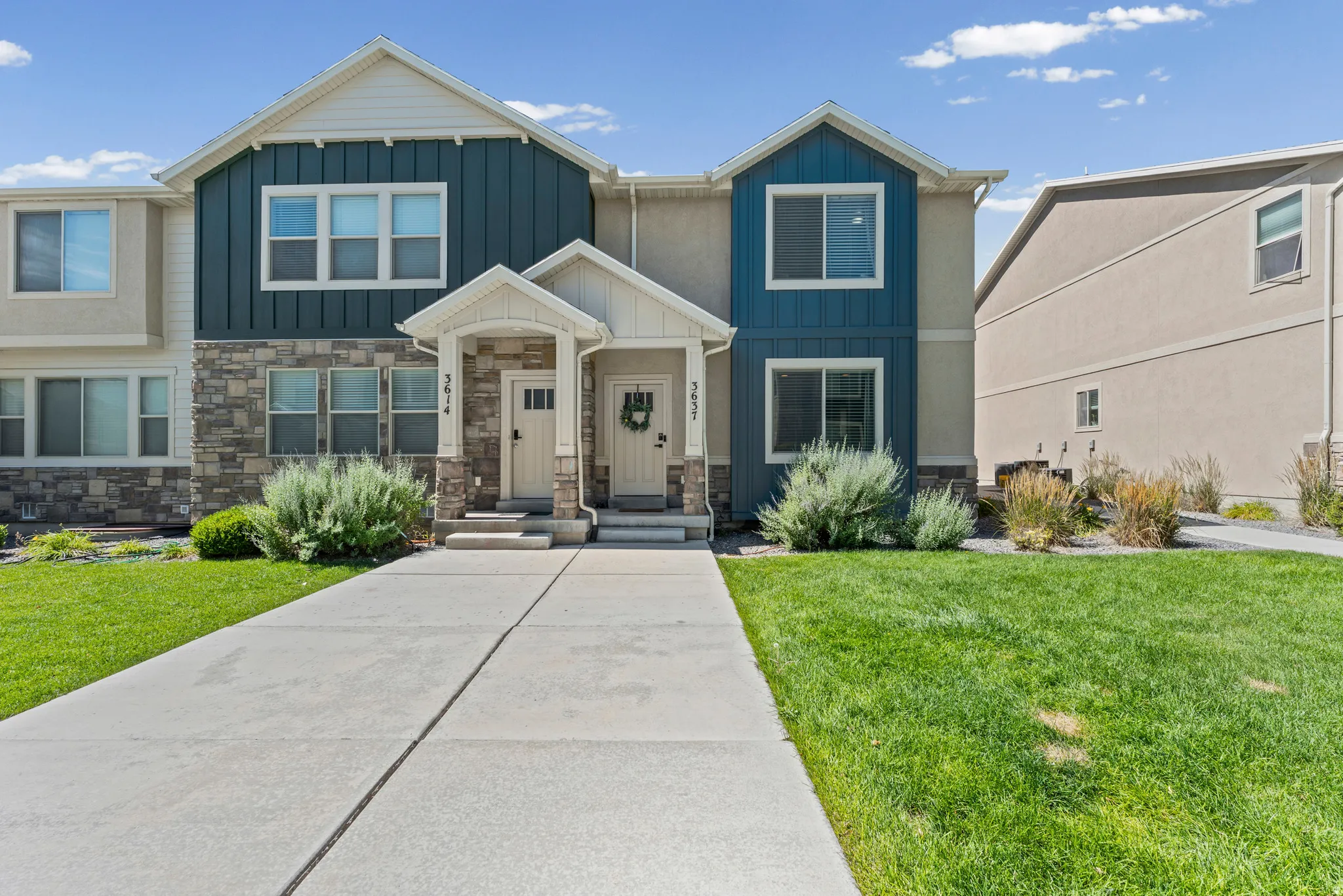 Modern townhome facade featuring vertical blue siding accents, stone veneer, and white trim