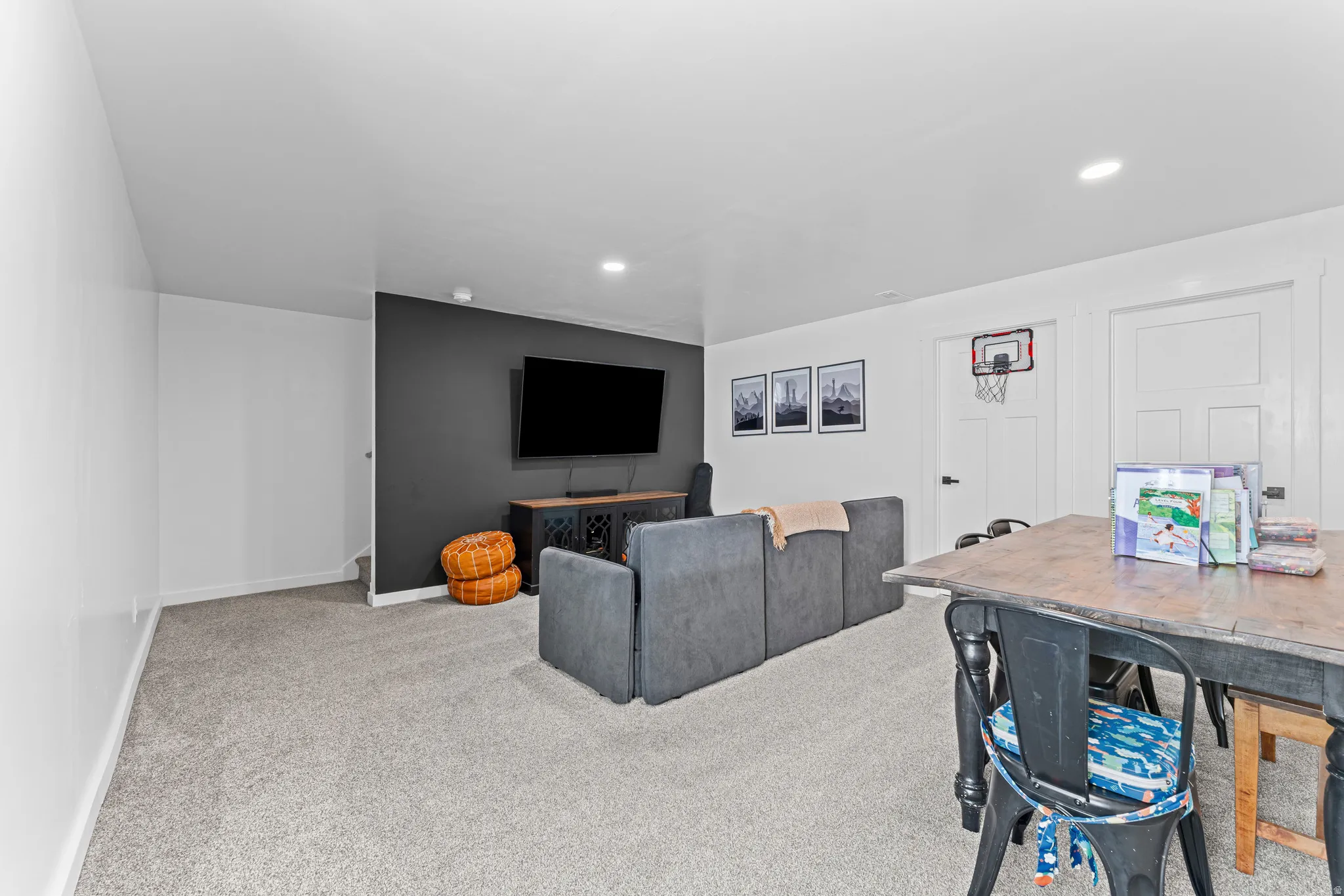 Spacious recreation room featuring light gray carpeting, recessed lighting, and a dark accent wall