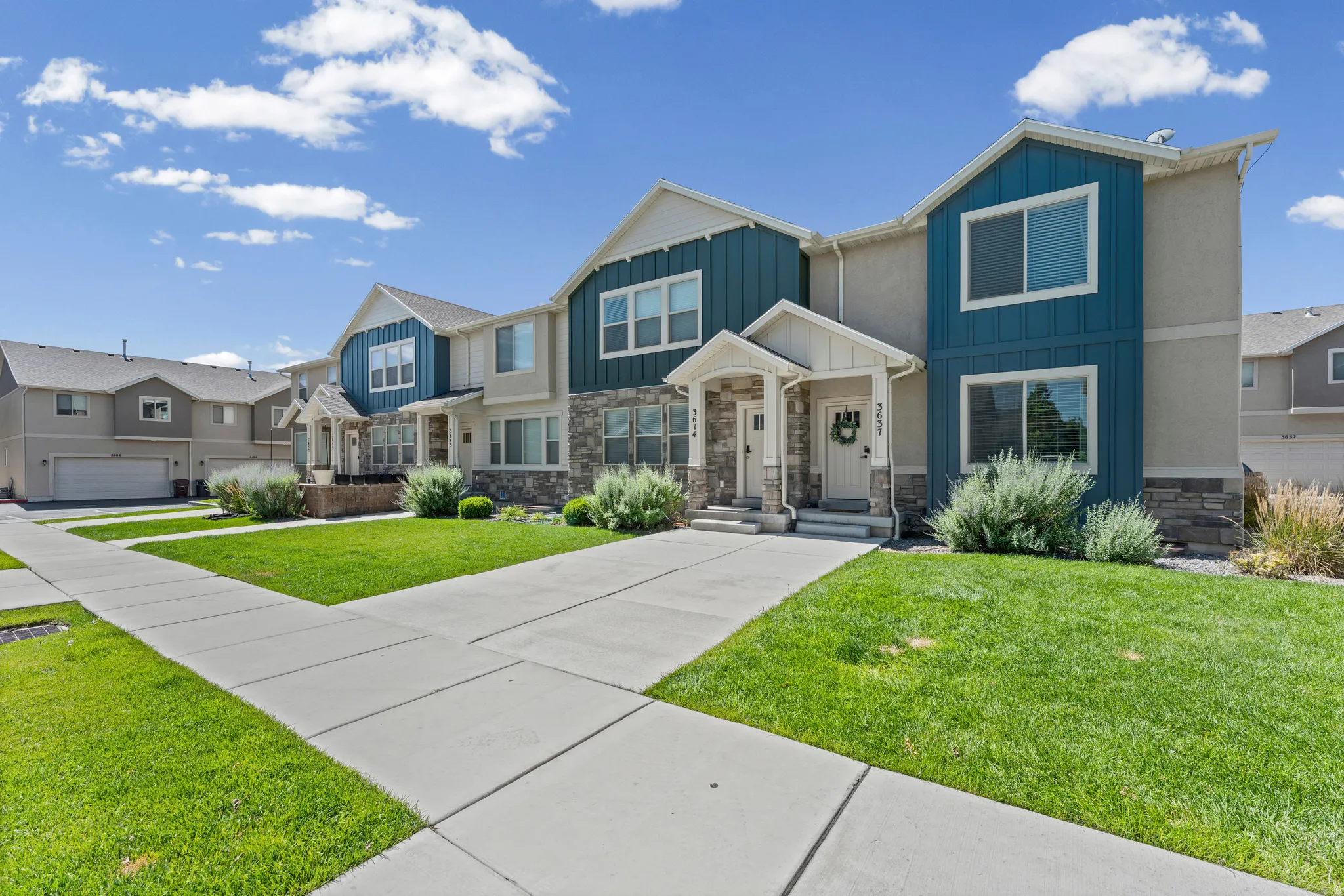 Townhome exterior featuring blue vertical siding accents, stone veneer detailing, and a covered entryway