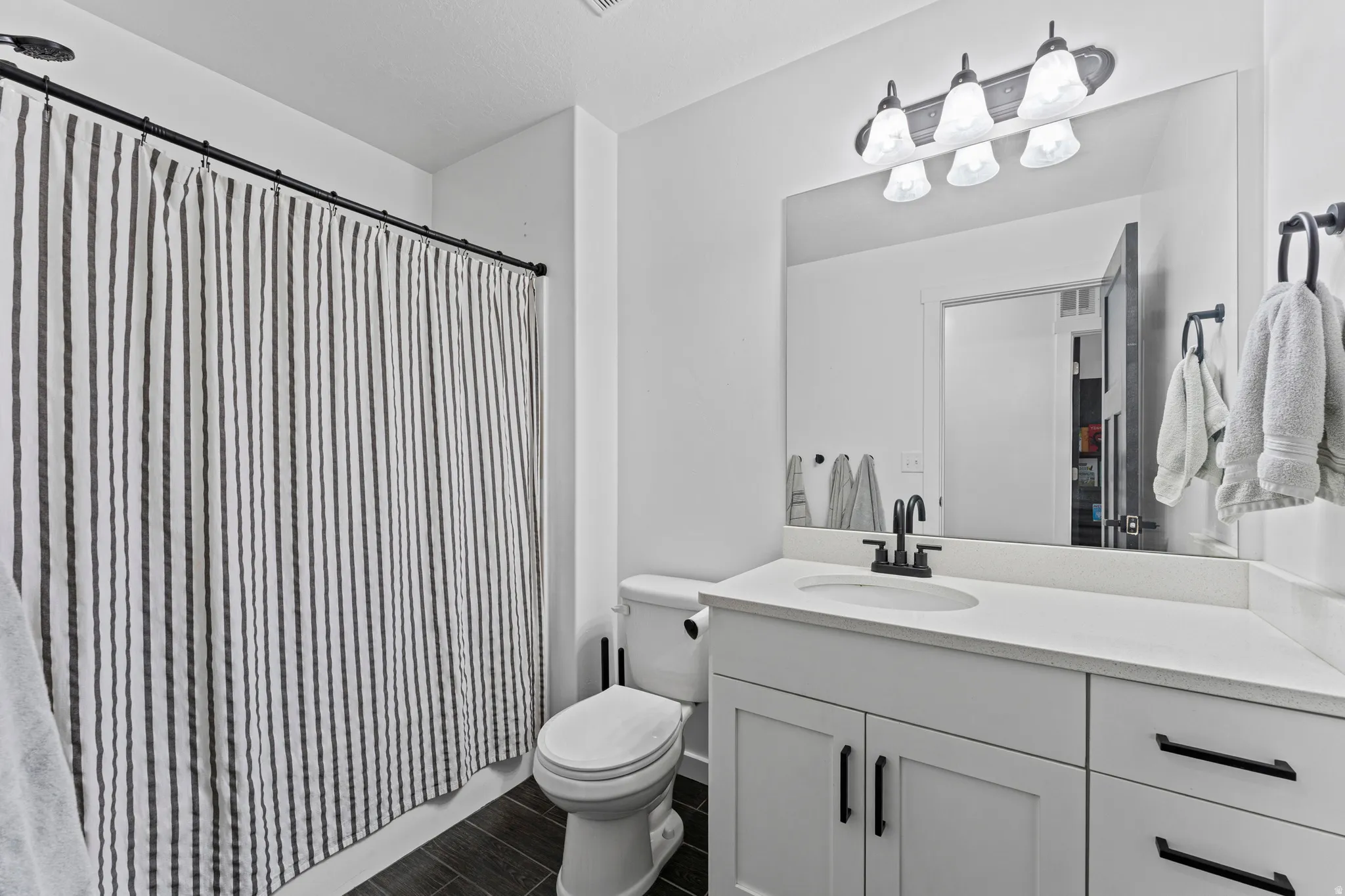 Bathroom featuring a white vanity with an undermount sink, a large wall mirror, and matte black fixtures