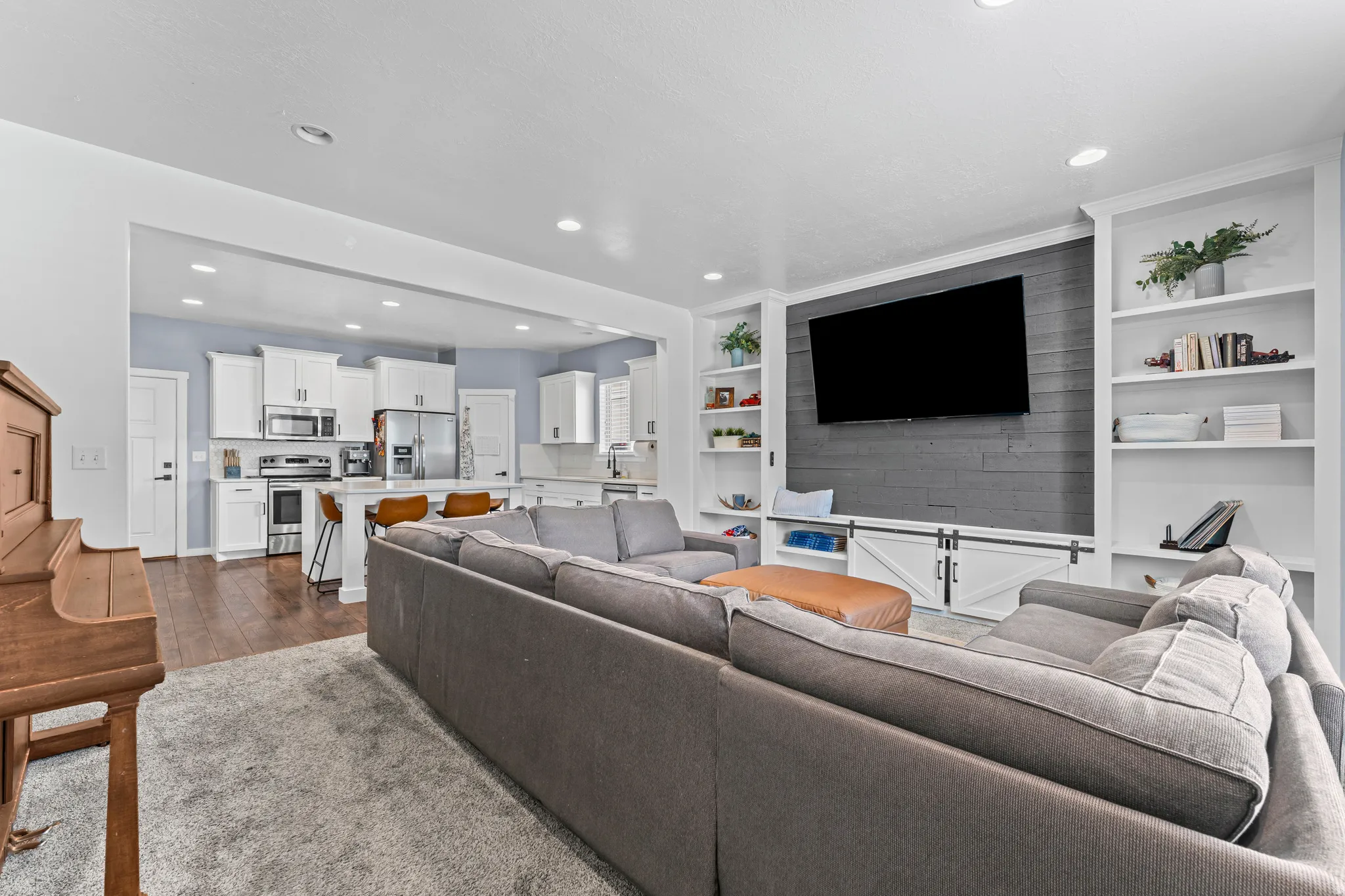 Open-concept living space featuring a built-in media center with shiplap accent wall, integrated shelving, and barn door cabinetry