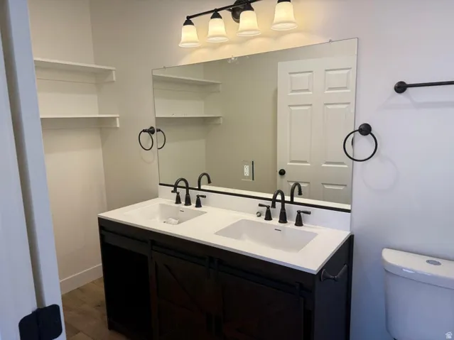 Dual vanity with a white countertop and integrated sinks, dark wood-finish cabinetry, and matte black fixtures