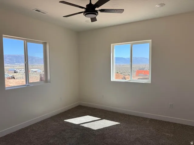 Bright interior space featuring two large windows, a ceiling fan with integrated lighting, recessed lighting, and carpeted flooring