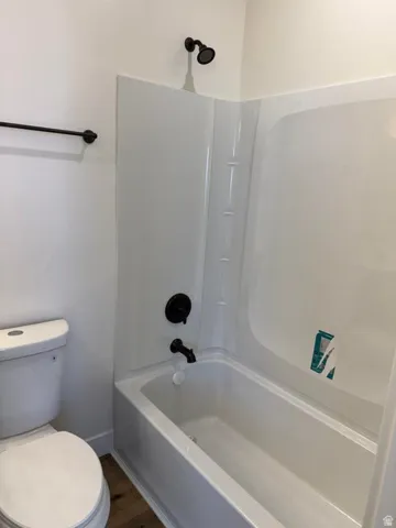 Bathroom featuring a white tub and shower combination with dark bronze fixtures