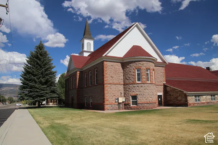 Stone and brick exterior featuring a prominent steeple, rounded turret, and a vibrant red roof