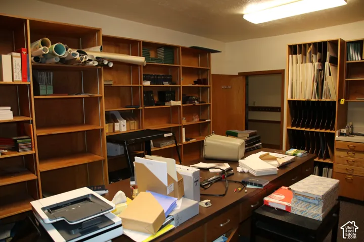 Expansive room featuring extensive built-in wooden shelving, a large wooden desk, and a utility cabinet with drawers