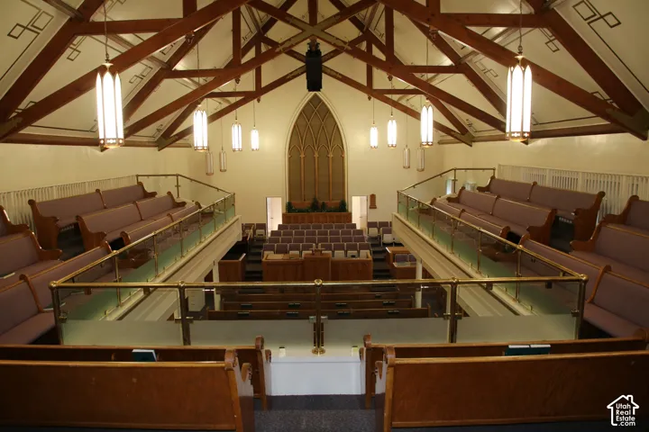 Spacious interior featuring a vaulted wood-beam ceiling, multi-tiered seating, and a large arched window