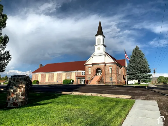 Brick and stone facade building featuring a prominent steeple, red-toned roofing, and a front entry with concrete steps