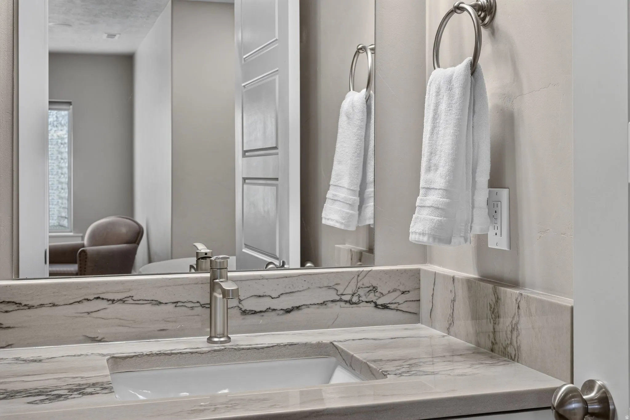 Vanity with an integrated rectangular sink, stone-finish countertop, and brushed nickel single-handle faucet