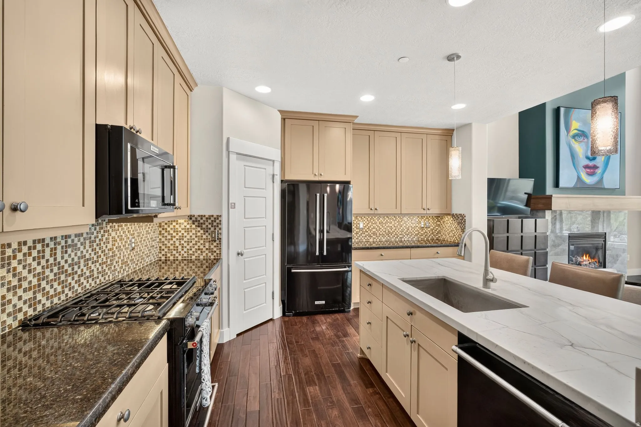 Gourmet kitchen featuring a large central island with an undermount sink, stone countertops, and dark wood-finish flooring