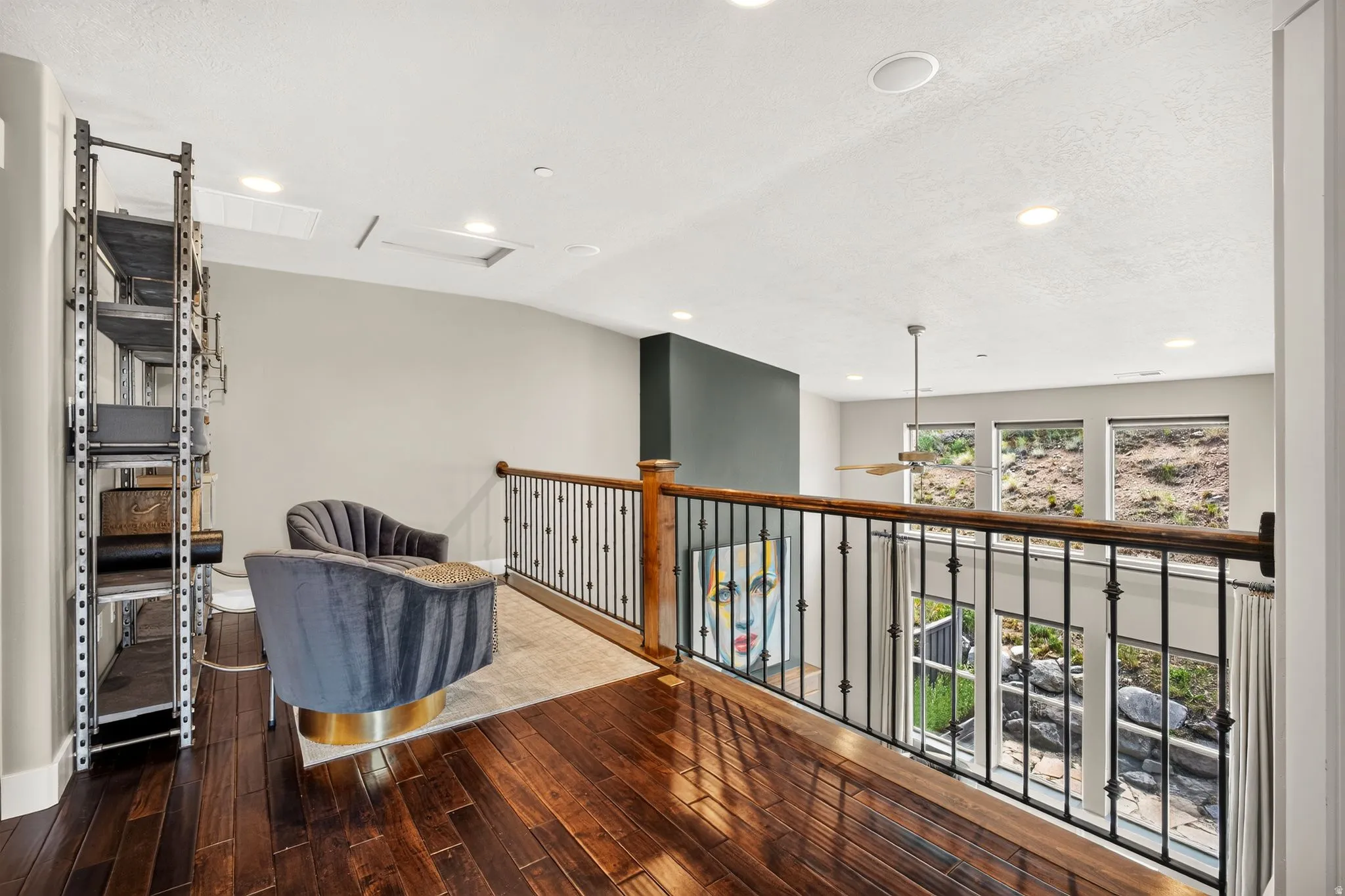 Loft area featuring rich wood-finish flooring, a dark iron balustrade with a wood handrail, and recessed lighting