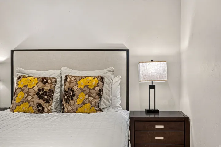 Upholstered headboard with a dark frame, flanked by a dark wood nightstand featuring two drawers with linear silver hardware