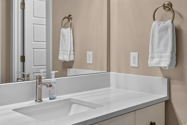 Bathroom vanity featuring an integrated rectangular sink, brushed nickel faucet, and white countertop with backsplash