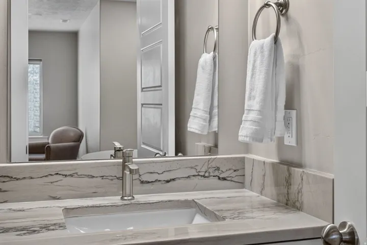 Vanity with an integrated rectangular sink, stone-finish countertop, and brushed nickel single-handle faucet