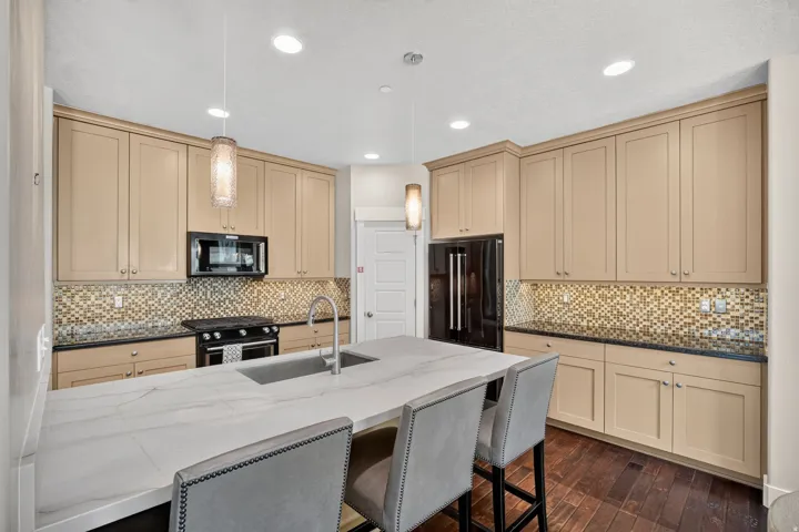 Kitchen featuring a central island with a built-in sink, stone countertop, and two pendant lights