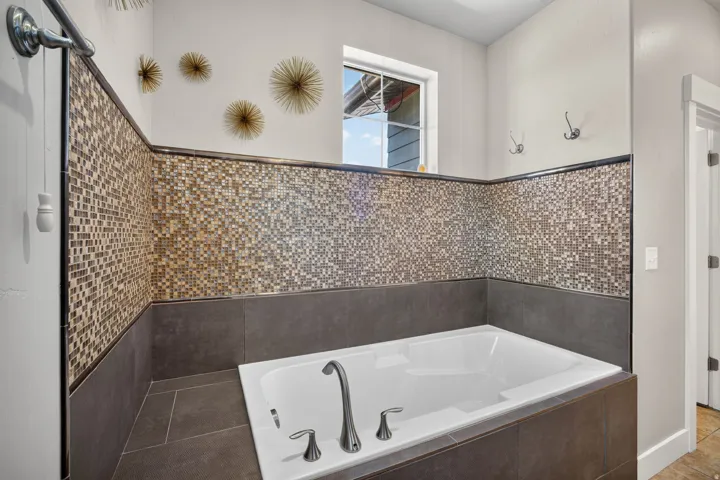 Soaking tub featuring a mosaic tile surround and brushed nickel fixtures