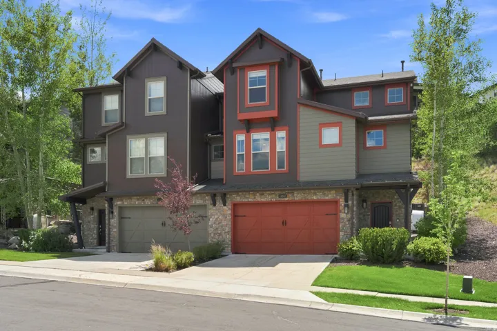 Contemporary townhome exterior featuring multi-toned siding, stone accents, and a prominent red garage door
