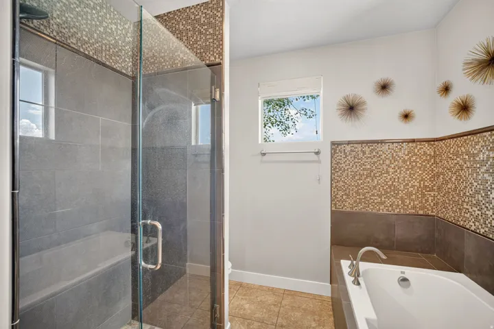 Bathroom featuring a glass-enclosed shower with a built-in bench, gray tile surround, and mosaic accent