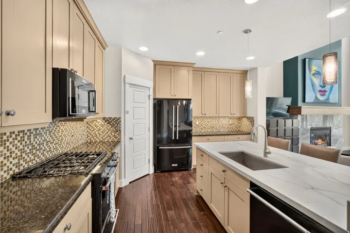 Gourmet kitchen featuring a large central island with an undermount sink, stone countertops, and dark wood-finish flooring