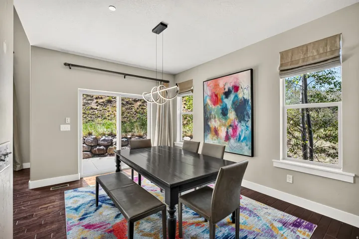 Dining area with dark wood-finish flooring, light-toned walls, and a contemporary chandelier