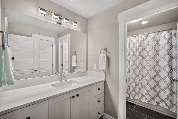 Spacious bathroom featuring a white vanity with an integrated sink, a large mirror, and a modern four-light fixture