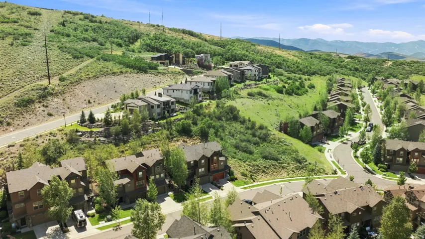 Aerial perspective showcasing a residential community nestled on a verdant hillside with paved streets and mature trees