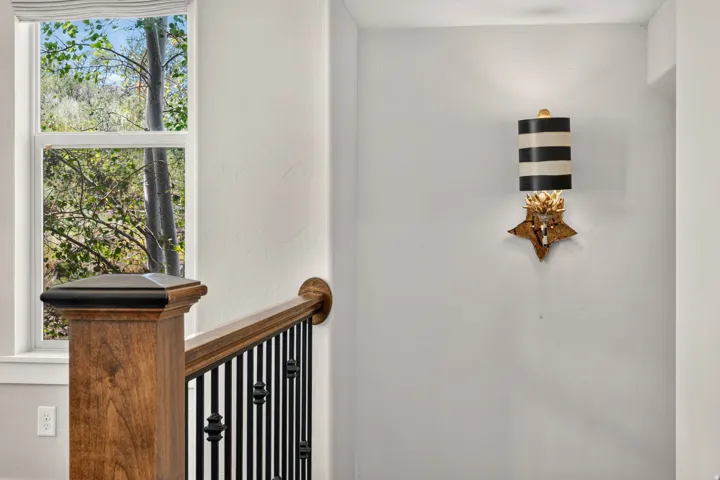Stairwell featuring a wood newel post and handrail with decorative black iron balusters
