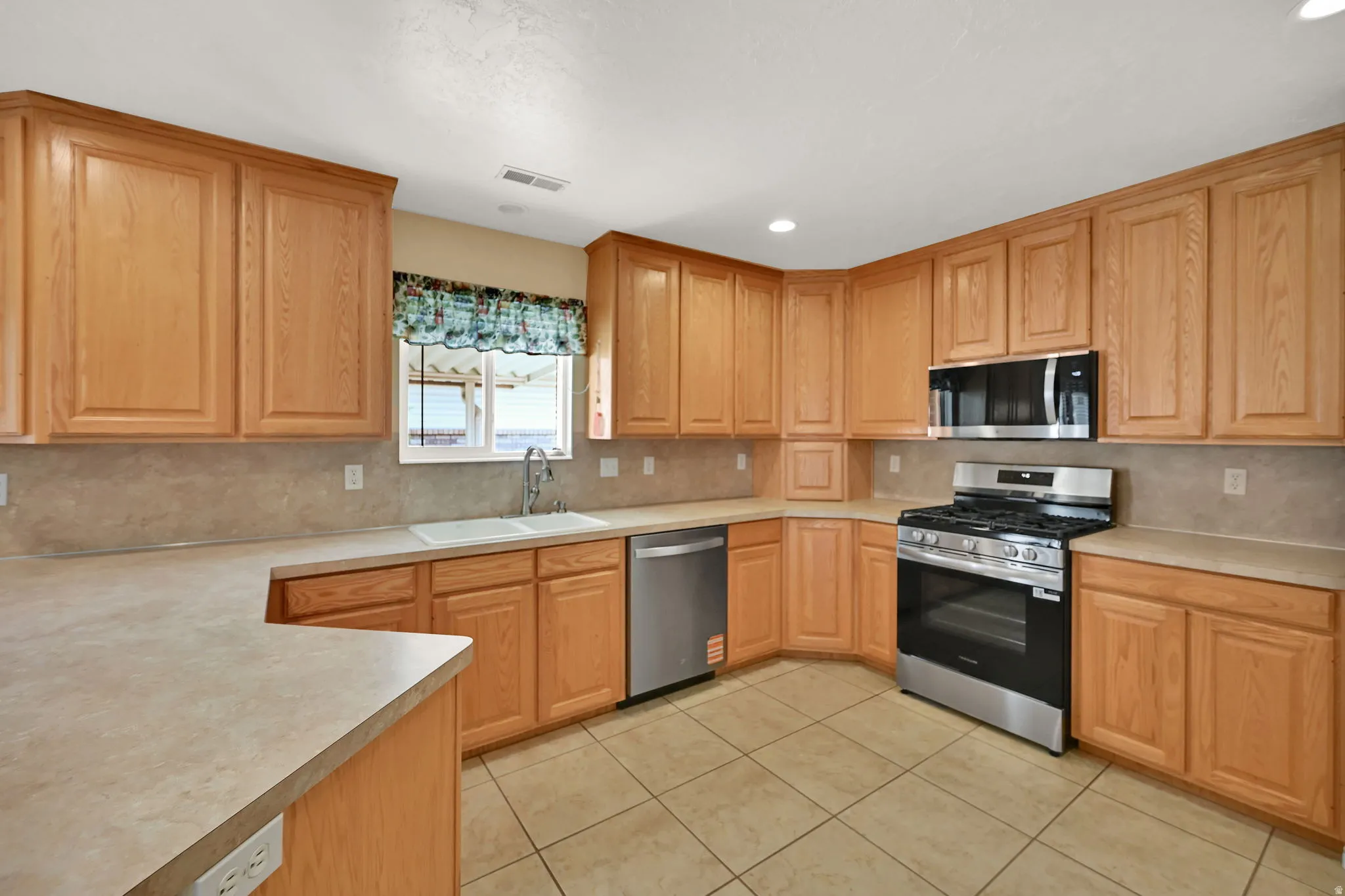 kitchen featuring tile flooring, and NEW  stainless steel suite including a gas range, microwave, and dishwasher