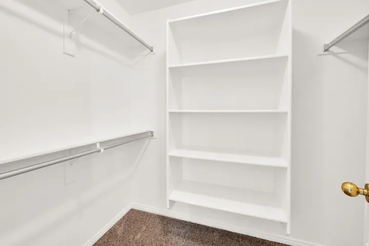 Walk-in closet featuring built-in shelving and dual hanging rods
