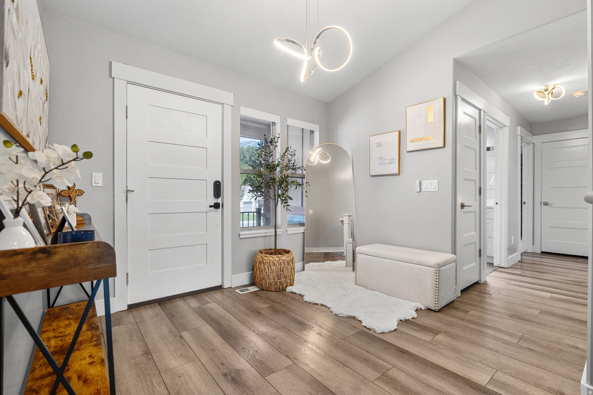 Entryway featuring durable wood-finish flooring, a contemporary pendant light fixture, and a white paneled door with modern hardware
