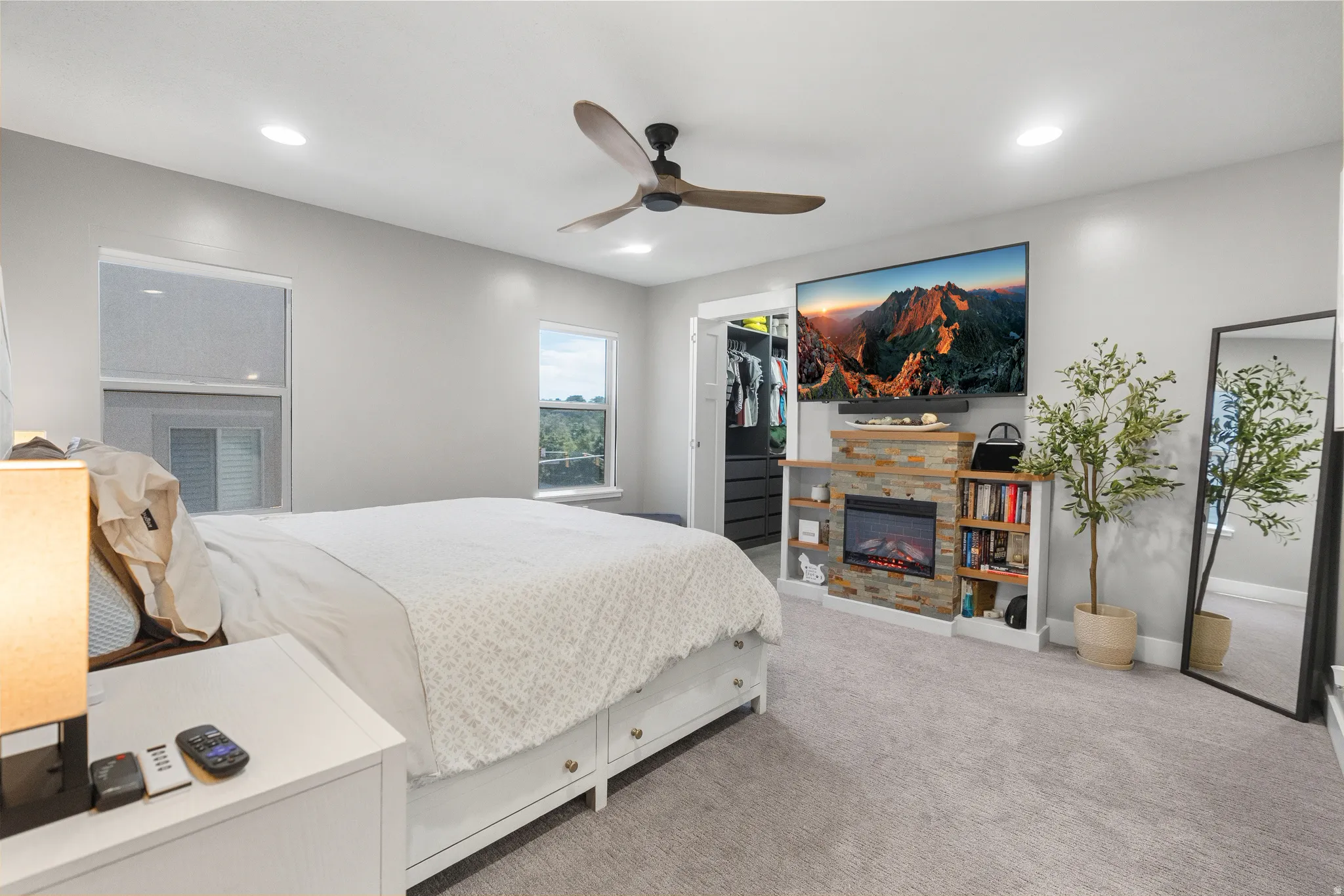 Spacious room featuring a stacked stone fireplace with an integrated entertainment center, recessed lighting, a ceiling fan, and carpet flooring