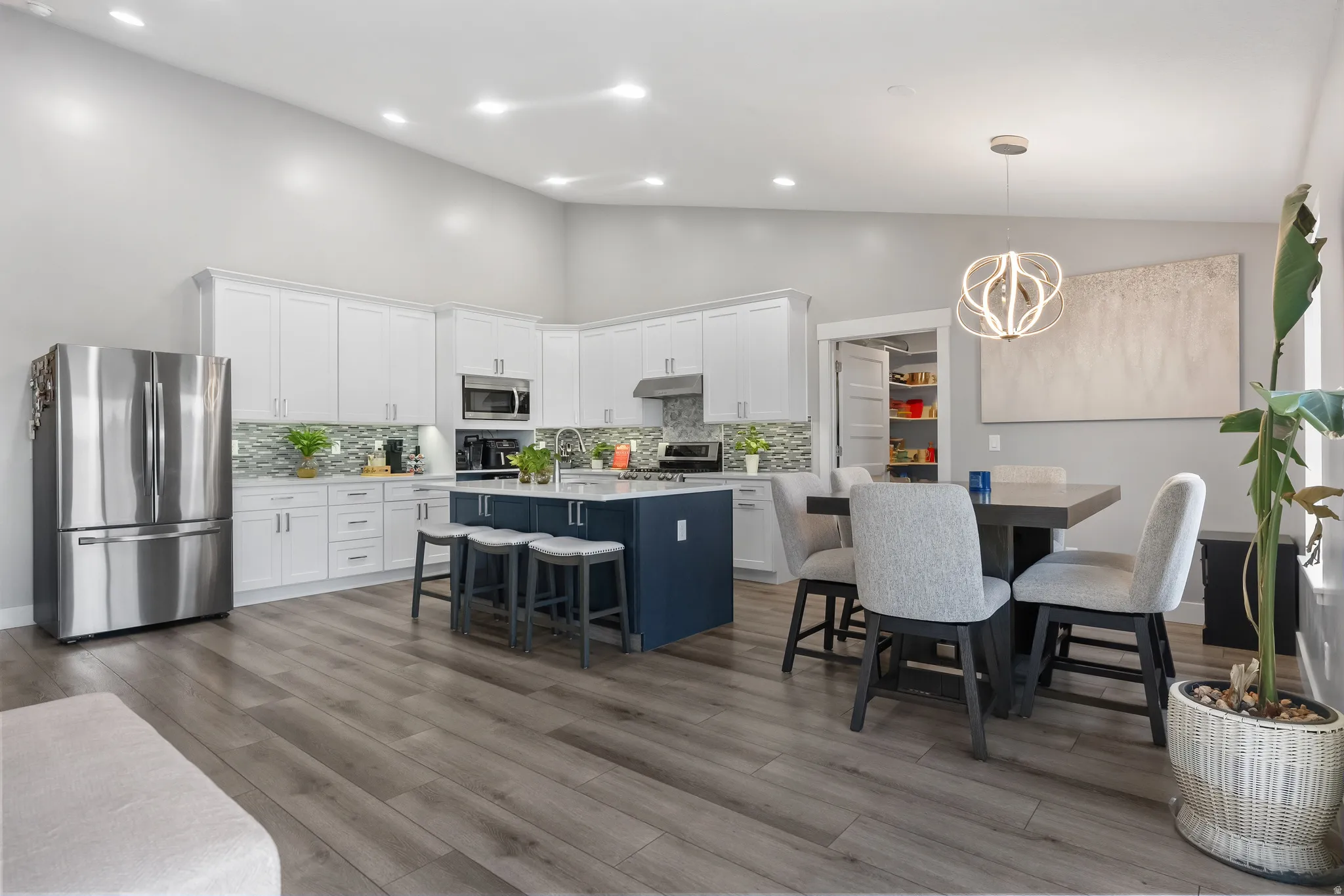Open-concept kitchen and dining area featuring a vaulted ceiling and wood-finish flooring