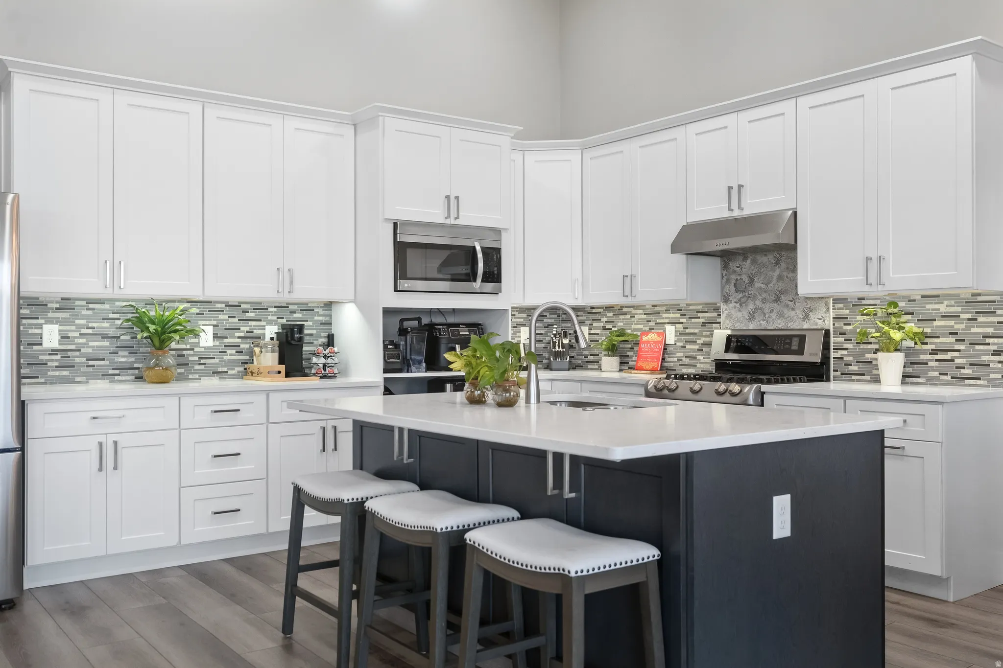 Modern kitchen featuring an expansive center island with seating, stainless steel appliances, and wood-finish flooring