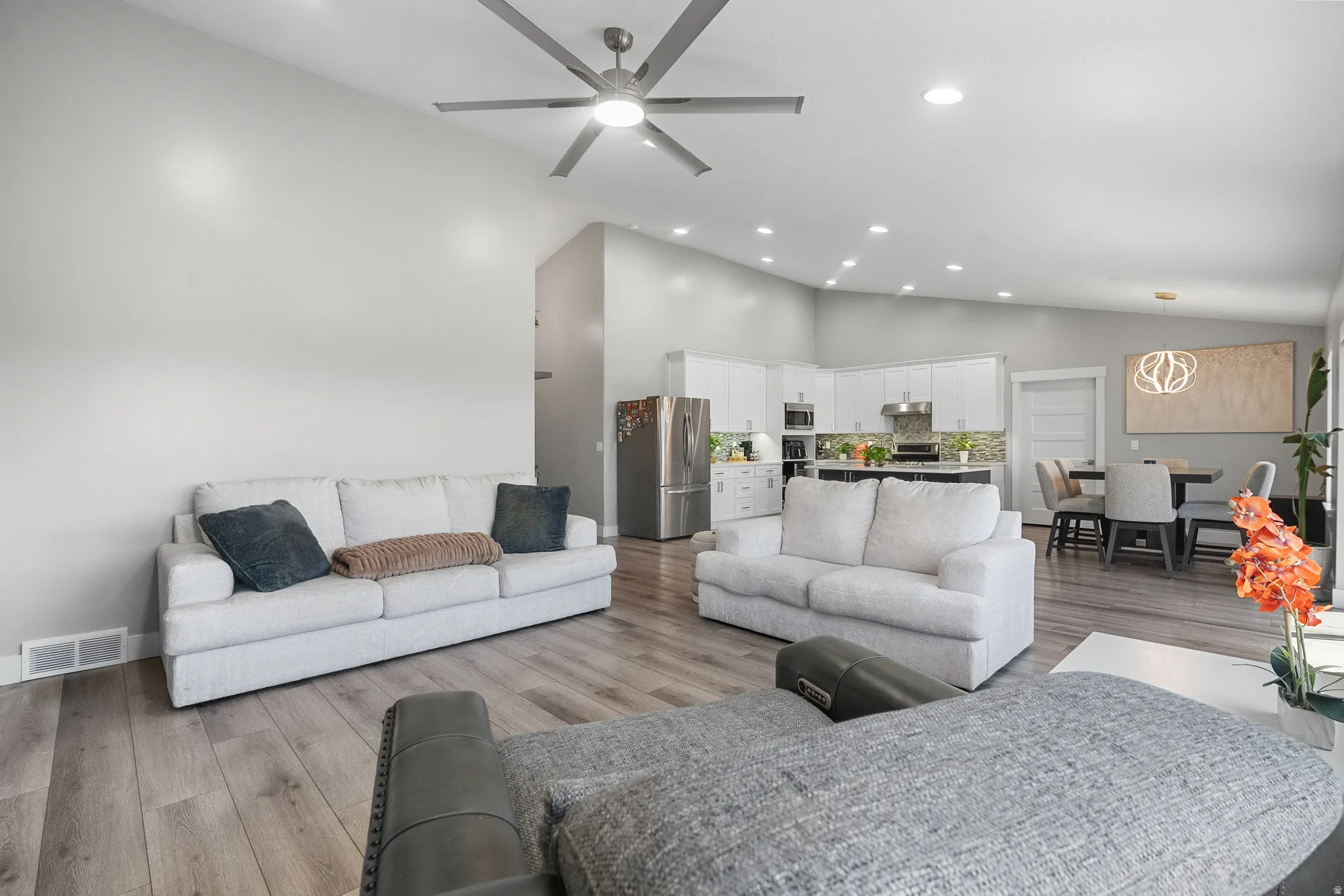 Open-concept living space featuring vaulted ceilings, wood-finish flooring, a modern ceiling fan, and recessed lighting