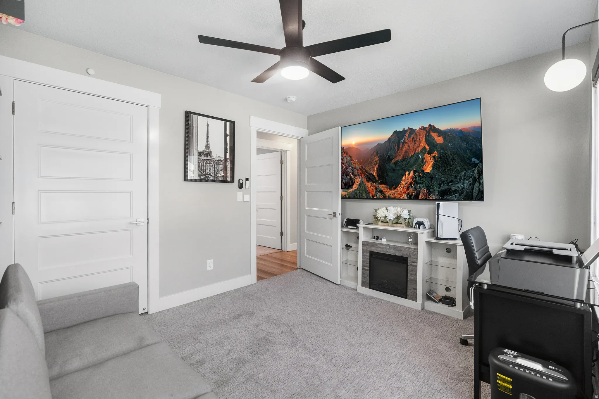 Carpeted room featuring a ceiling fan, wall-mounted television, and a built-in media console with an electric fireplace