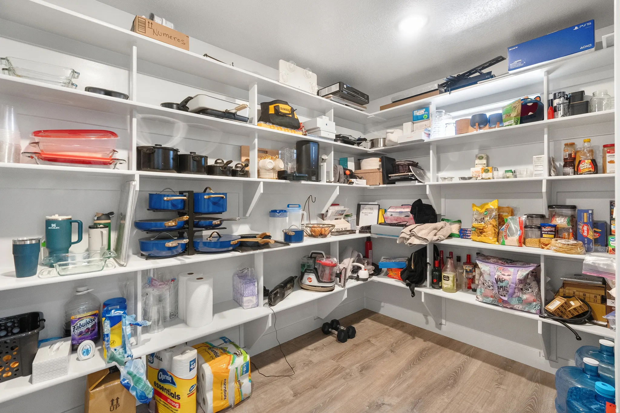 Walk-in pantry featuring extensive built-in shelving, recessed lighting, and wood-finish flooring
