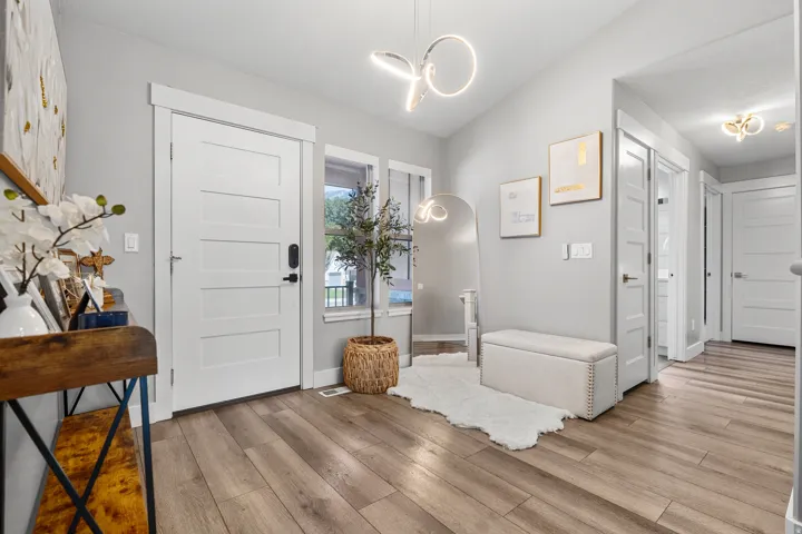 Entryway featuring durable wood-finish flooring, a contemporary pendant light fixture, and a white paneled door with modern hardware