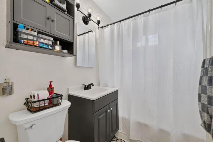 Bathroom featuring a dark gray vanity with integrated sink, coordinating wall-mounted cabinet, and a multi-bulb vanity light fixture