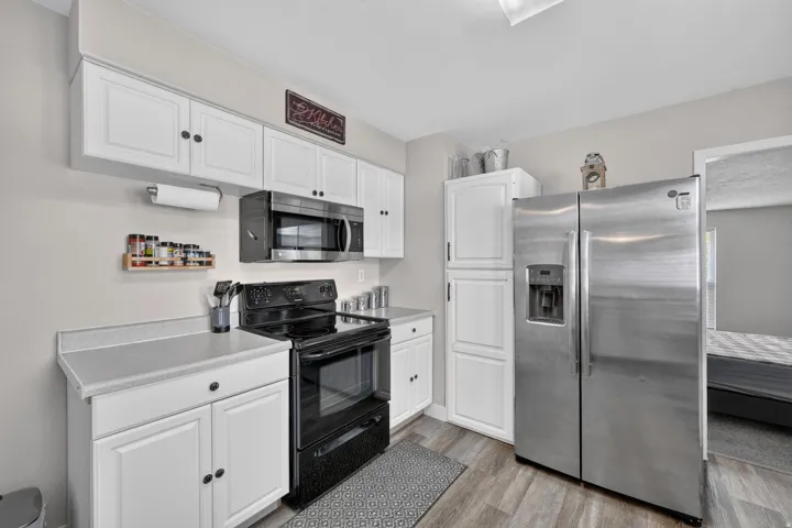 Contemporary kitchen featuring white cabinetry, light countertops, and wood-finish flooring