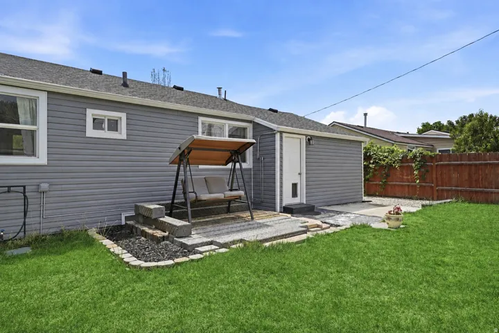 Expansive green lawn, gray horizontal siding, and a wooden fence
