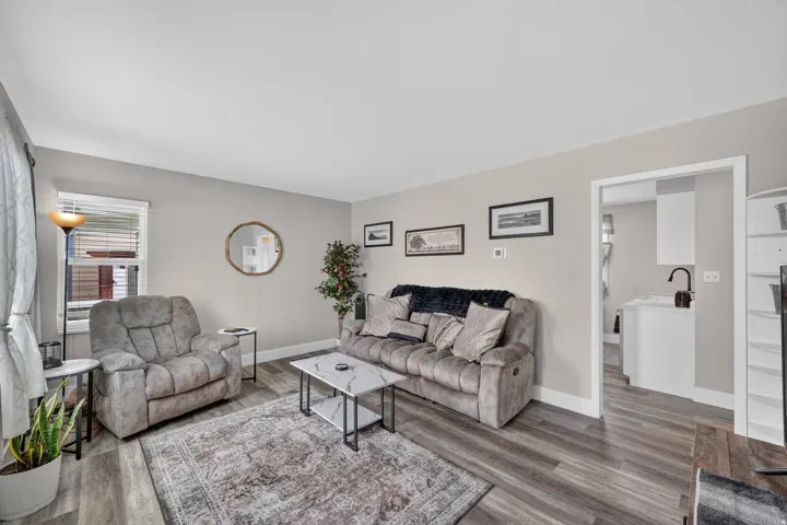 Living area featuring wood-finish flooring, light neutral wall tones, and white trim