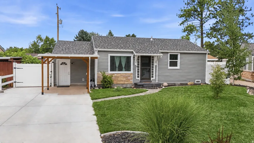 Gray siding exterior with a shingled roof, a covered entry, stone facade accents, and a concrete driveway